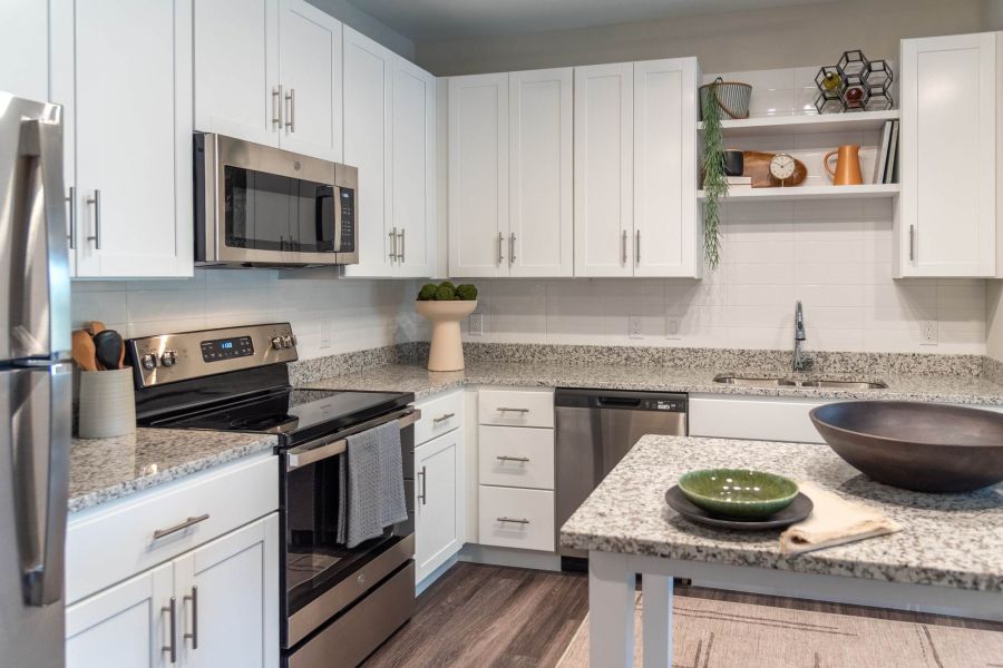 Attain at Towne Centre  apartment homes with Modern kitchen with white cabinets, stainless steel appliances, and granite countertops.