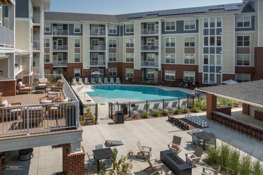 Attain at Towne Centre apartment homes with Modern apartment complex courtyard with swimming pool, lounge chairs, fire pit, and outdoor chess set.