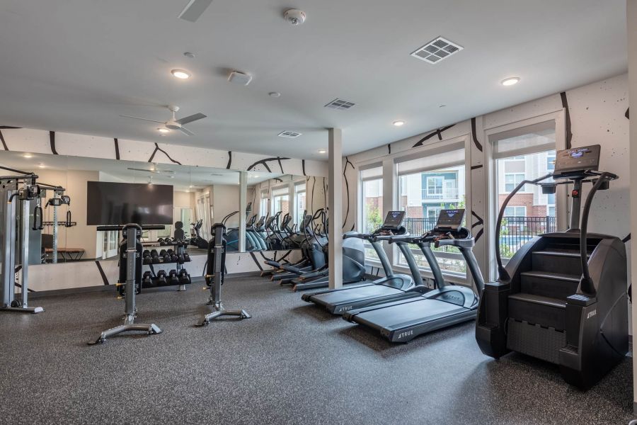 Attain at Towne Centre apartment homes with Modern gym with treadmills, stair climber, weights, and exercise machines in a bright, spacious room.