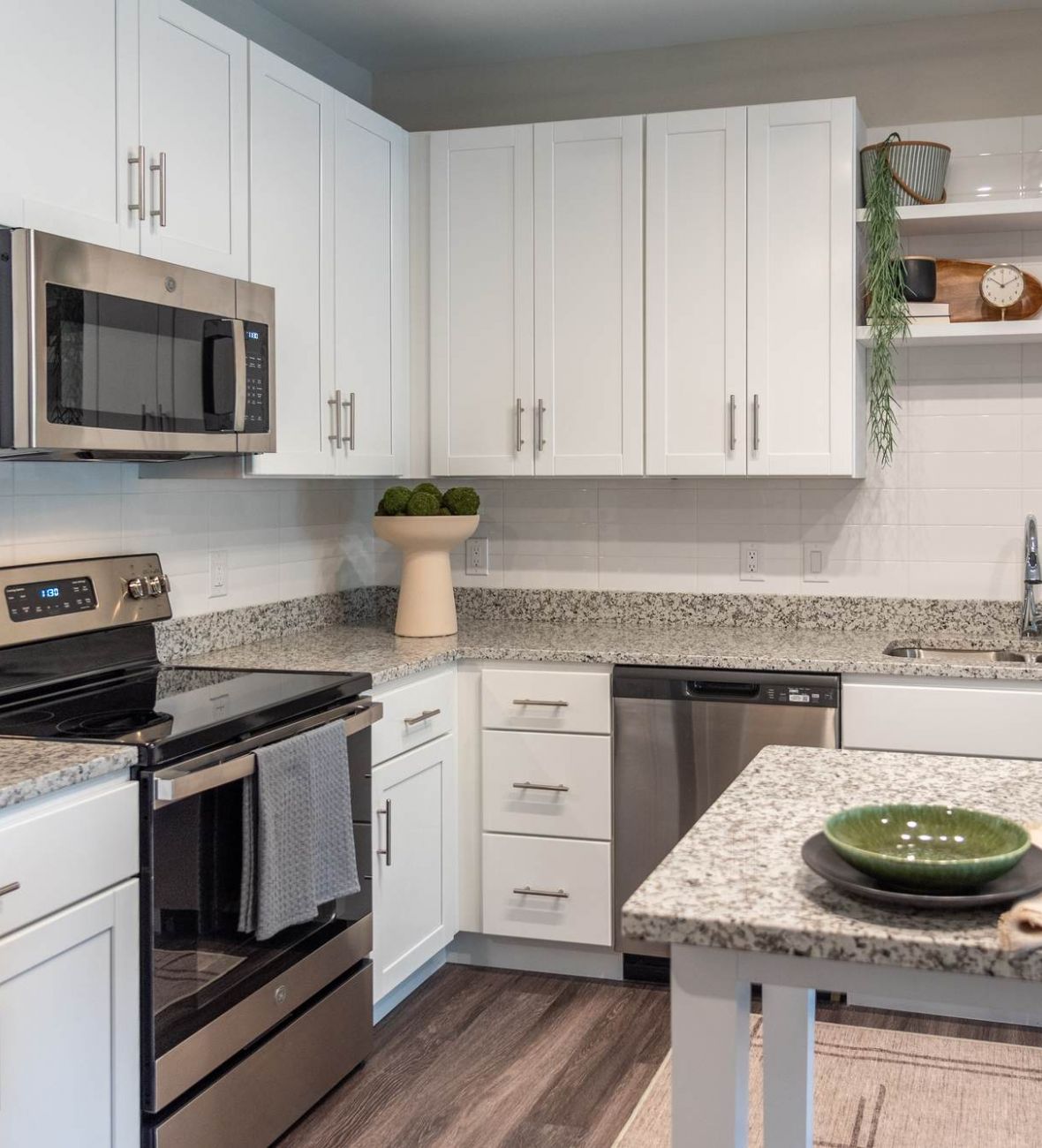 Attain at Towne Centre apartment homes with Modern kitchen with white cabinets, stainless steel appliances, and granite countertops.
