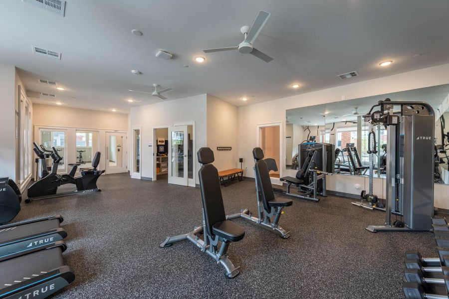 Attain at Towne Centre apartment homes with Modern gym with treadmills, weight machines, benches, mirrors, and large windows for natural light.