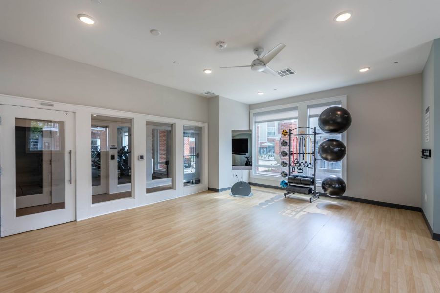 Attain at Towne Centre apartment homes with Bright fitness room with wood floors, wall mirrors, exercise balls, and large windows.